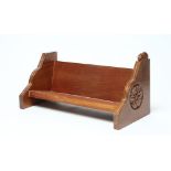 A PETER HEAP OAK BOOK TROUGH, the moulded tapering end supports each carved with a Yorkshire rose
