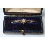A PEARL BROOCH, the open propellor frame centred by a small flowerhead with diamond point, unmarked,