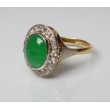 AN EMERALD AND DIAMOND DRESS RING, the oval cabochon polished emerald open back collet set to a