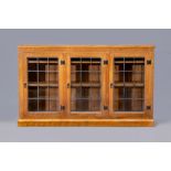 A WILF HUTCHINSON ADZED OAK BOOKCASE of low oblong form with three leaded glazed doors enclosing