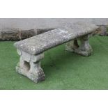 A COMPOSITE STONE BENCH, the oblong seat carved in low relief with a frieze of cherubs merry making,