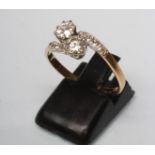 A TWO STONE DIAMOND CROSSOVER RING, the round cut stones each of approximately 0.5cts claw set to
