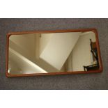 A DANISH DESIGN TEAK FRAMED WALL MIRROR, 1960's, of rounded oblong form, 26" x 50" (Est. plus 21%