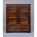 A JOINED OAK PANELLED LIVERY CUPBOARD, early 18th century, carved scrolling foliate and chequer