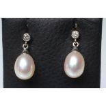 A PAIR OF PEARL DROP EARRINGS, the oval pearls with white gold caps pendant from a solitaire diamond
