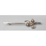 A DIAMOND AND PEARL BAR BROOCH, the old facet cut oval diamond open back collet set to a clover leaf