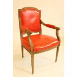 A LOUIS XVI STYLE BEECH ELBOW CHAIR, c.1900, upholstered in red leather, the channelled frame with