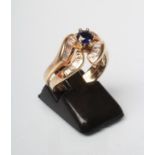 A SAPPHIRE AND DIAMOND DRESS RING, the central facet cut sapphire claw set to open stylised petal