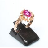 A RUBY COCKTAIL RING, the oval facet cut stone claw set to a frilled mount and cast shoulders to a