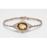 AN EDWARDIAN BRACELET, the convex filigree lozenge panel claw set with an oval facet cut citrine