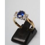 A SAPPHIRE AND DIAMOND THREE STONE RING, the central oval facet cut sapphire claw set and flanked by