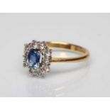 A SAPPHIRE AND DIAMOND CLUSTER RING, the square cut sapphire claw set to a border of ten small round
