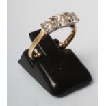 A THREE STONE DIAMOND RING, the central brilliant cut stone of approximately 0.25cts claw set and