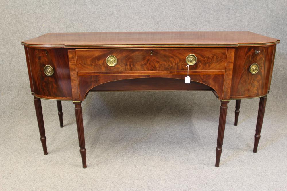 A GEORGIAN MAHOGANY SIDEBOARD, c.1800, of bowed breakfront form with brass trim and stringing,