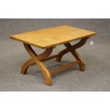 A PETER HEAP ADZED OAK COFFEE TABLE, of rounded oblong form raised on curved X framed end supports