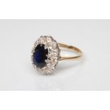 A SAPPHIRE AND DIAMOND CLUSTER RING, the oval facet cut sapphire claw set to a border of twelve