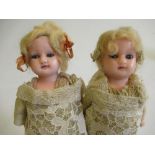 A pair of wax head and shoulder dolls, with blue glass inset eyes, closed mouths, fabric bodies,