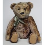 An early shoe button eyed teddy, possibly German, with sewn nose, felt pads, blue plush, bow and