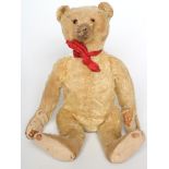 A Steiff teddy, c.1920, with glass eyes, felt pads, red bow and straw stuffing, 12" high (Est.