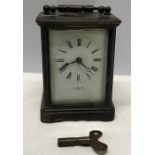 Black painted brass cased carriage clock with key, enamel face retailer H.W. Bedford, London.