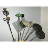 A collection of 12 long hat pins including 1912, 1913, 2 circular black with swallows, 1 mother of