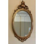 Decorative gilt framed oval wall mirror. 79cms h x 41cms w.