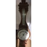 A light oak carved aneroid barometer, C1900 with white porcelain dial and thermometer scale.