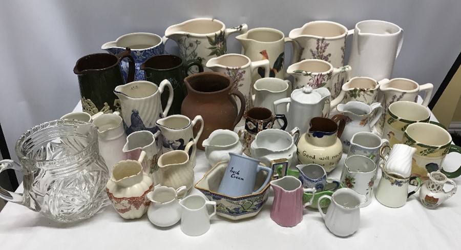 A large collection of ceramic jugs with 2 mugs and 1 glass jug.