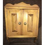 A two door pine wall cabinet.