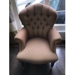 Well upholstered armchair on turned front legs with brass castors.