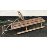 Metal and pine framed sledge with steering wheel and handbrake. 108cms l.