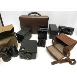 Five various vintage cameras and a brown case with military binoculars. Eanemannm Soho-pilot.