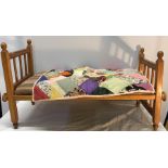 Children's dolls wooden cot bed with a small patchwork quilt.