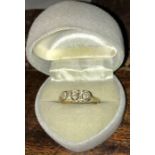 An 18ct 3 stone diamond ring with smaller diamonds around them. 2.5gms gross.