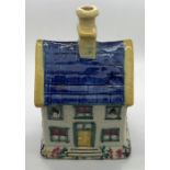 An early 19thC Prattware moneybox modelled as a cottage with figures in the window and a figure with