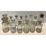 Fourteen various clear glass pharmacy bottles with stoppers, tallest 16cms h to include Sodium