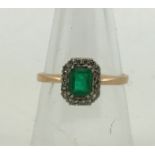 An emerald and diamond ring, four claw set emerald surrounded by diamonds, shank stamped 585,