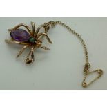 A vintage spider brooch with purple stone to body and green to head, marked 9 carat with safety