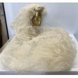 An early 20thC bridal veil with hairband attached with wax and fabric leaves and flowers.Condition