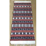 A black, red and white patterned Kilim, 135 x 56cms.