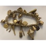 A 9 ct gold charm bracelet with 21 9 ct gold charms. 63gms.