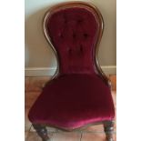 A mahogany spoon backed upholstered nursing chair on bun feet with castors. Button backed