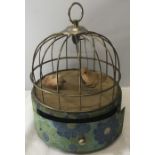 A 1960's birdcage music box, plays the theme from 'Love Story' as a bird swings back and forth.