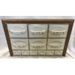 A French kitchen spice and food cupboard, the labelled ceramic drawers fitted in a wooden frame.