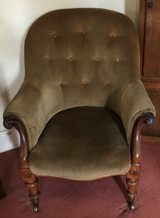 An upholstered Victorian armchair with turned legs, scroll arms on brass with original castors.