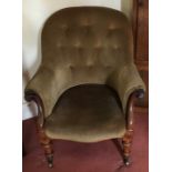 An upholstered Victorian armchair with turned legs, scroll arms on brass with original castors.