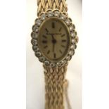 A 9 ct gold ladies Bueche Girod wristwatch, the oval face surrounded by diamonds. 23gms total