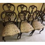 A set of six walnut balloon backed chairs with ornate carving to back on cabriole legs.