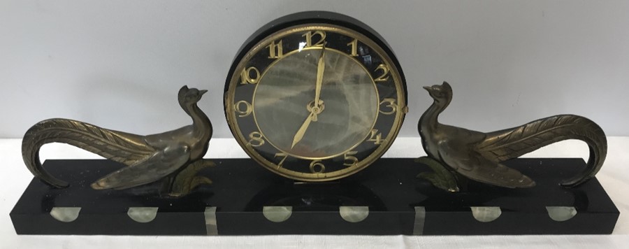A French Art Deco mantle clock on a black marble onyx base with gilt metal confronting peacocks.