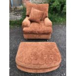 Burnt orange upholstered armchair with matching footstool.